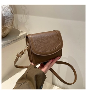 Detail of dark brown pebble grain leather surface with elegant gold metal buckle hardware