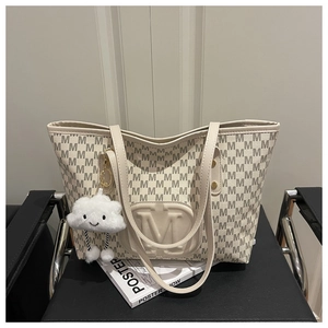 Detail of cream tote bag with letter M embossed logo and cute cloud plush keychain accessory