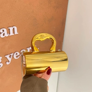 Elegant gold acrylic cylinder handbag with sculptural metal handle and crossbody chain