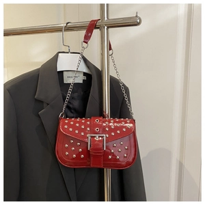 Detail of dark red patent leather shoulder bag with silver studs and chain strap