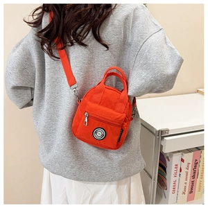 Detail of orange nylon crossbody bag with front zipper pocket and adjustable strap