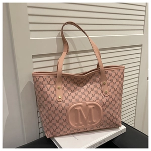 Detailed view of pink tote bag with M-pattern print on elegant white pedestal
