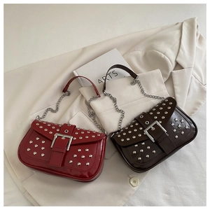 Close-up of wine red and dark brown patent leather bags with silver studs and chain straps