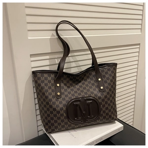 Close-up of vintage brown monogram pattern and embossed M logo on a large tote bag