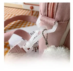 Close-up of pink canvas bag featuring a white detachable hook and a plush bear pendant