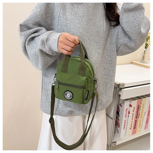 Detailed view of the green nylon handbag with top handles and adjustable shoulder strap