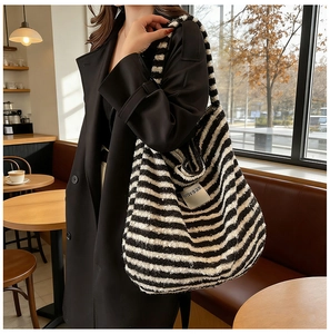 Detail of a large black and white striped knit tote bag with a woven brand tag