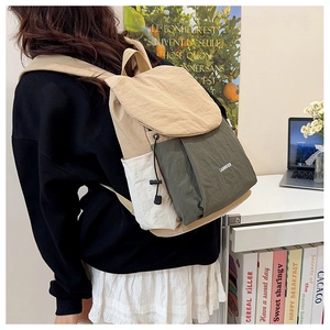 Detailed back view of a minimalist khaki and green canvas backpack in a cozy study setting