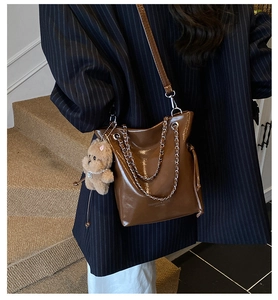 Detail view of brown oil wax leather bucket bag with silver chain and cute bear charm