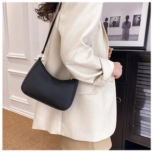 Detalle de un bolso hobo minimalista de cuero negro con herrajes dorados y costuras finas