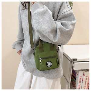 Close-up of a green nylon mini crossbody bag worn by a model in a casual setting
