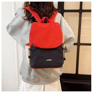 Detail view of large red and black travel backpack with brand logo on a model back
