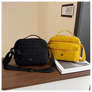 Detail of nylon crossbody bags in black and yellow showing triple zipper layers and metal logo