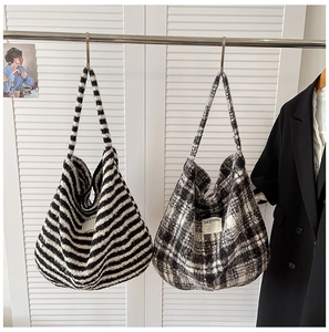 Detail of plush crossbody bags with stripe and plaid patterns hanging on a metal rod