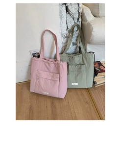 Detail of minimalist drawstring tote bags in pink and green with front flap pocket