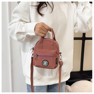 Detail of the pink nylon crossbody bag showing the adjustable strap and zipper pockets