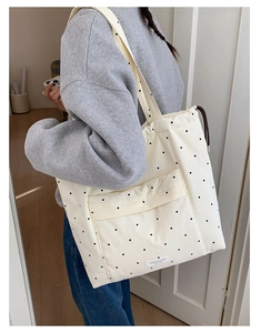 Detail of off-white canvas tote bag with black polka dots and side drawstring feature