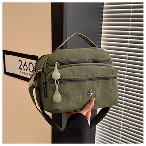 Detail of army green nylon crossbody bag showing pleated texture and multi-zipper pockets