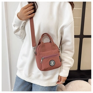 Detail view of pink-brown nylon crossbody bag with wide shoulder strap and brand logo