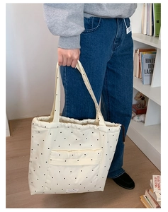 Detail of cream canvas tote bag featuring black polka dots and drawstring closure