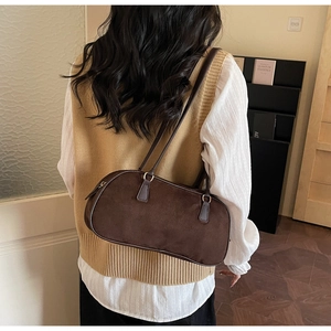 Close-up detail of dark brown suede shoulder bag with thin straps and metallic rings