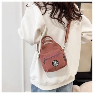 Model back view showing the dusty rose nylon crossbody bag with adjustable strap