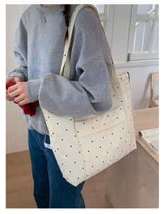 Close-up of cream polka dot tote bag with front pocket and durable nylon shoulder straps
