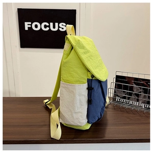 Detail of the color-block travel backpack showing side pockets and wrinkled fabric texture