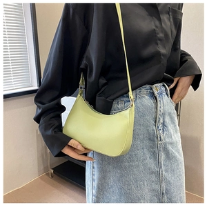Detalle de un bolso de hombro media luna verde claro en cuero sintético sobre una modelo