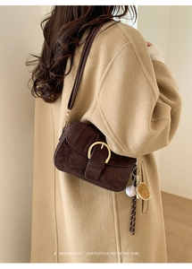 Close-up of retro suede brown handbag with gold horseshoe buckle and vintage charms