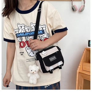 Detail of canvas crossbody bag with plush bear charm and cute badges for students