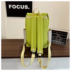 Detail view of lightweight neon green nylon backpack with beige straps on wooden surface
