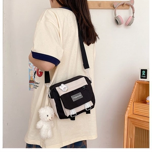 Detail of canvas crossbody bag with cute bear plush charm and fashion label tag