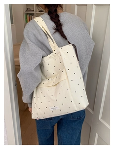 Detail showing the white canvas polka dot tote bag with drawstring and wide shoulder strap