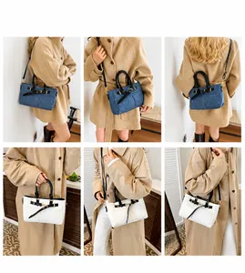 Detail view of denim and white faux leather crossbody bags with gold hardware buckles