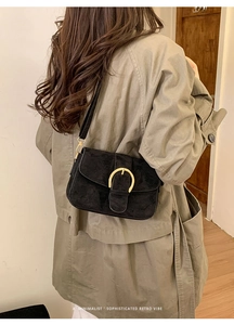 Minimalist black suede shoulder bag with retro gold metal buckle worn with a trench coat