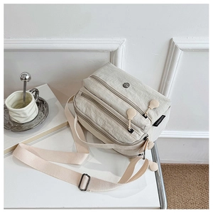 Detailed view of large capacity beige nylon shoulder bag with three zipper compartments