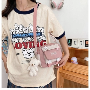 Detail of pink and white canvas crossbody bag with a cute bear pendant on a model