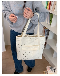 Close-up of beige polka dot tote bag with drawstring closure and front pocket detail