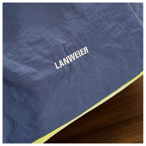 Detailed close-up of dark blue nylon fabric with white LANWEIER embroidery and neon trim