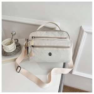 Detail of off-white multi-layer crossbody bag with zippers and metal logo on white desk