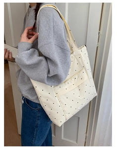 Detailed view of white canvas tote bag with black polka dots and spacious outer pocket