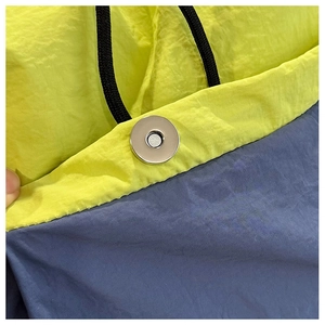 Detail shot of the magnetic snap closure and drawstrings on a two-tone nylon backpack