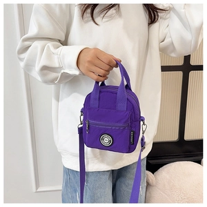 Detail view of purple nylon crossbody bag featuring adjustable straps and front zip pocket
