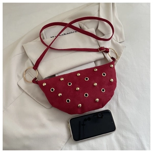 Détail du sac lune en daim rouge avec rivets dorés et un smartphone pour comparer la taille