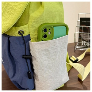 Close-up of color-block travel backpack side pocket showing functional phone storage