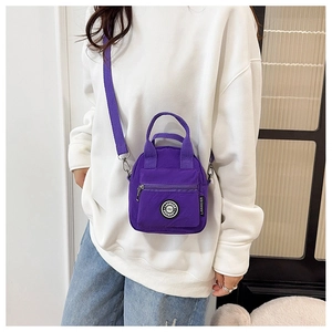 Detail of purple nylon crossbody bag featuring front zipper pocket and adjustable strap