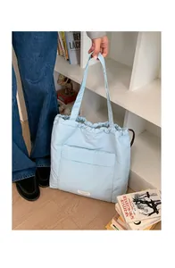 Detail of light blue quilted tote bag with drawstring closure and white woven label