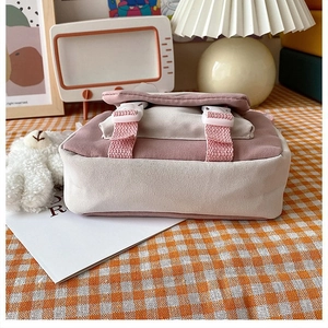 Detailed view of a cute pink and beige canvas crossbody bag on a warm plaid background