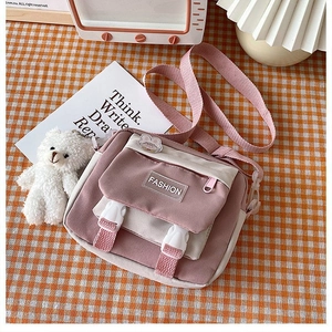 Close-up of pink and cream canvas crossbody bag with cute teddy bear and rabbit charm